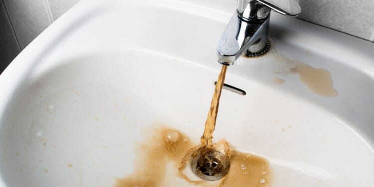 Brown, dirty sink water flows into a sink in this stock photo.