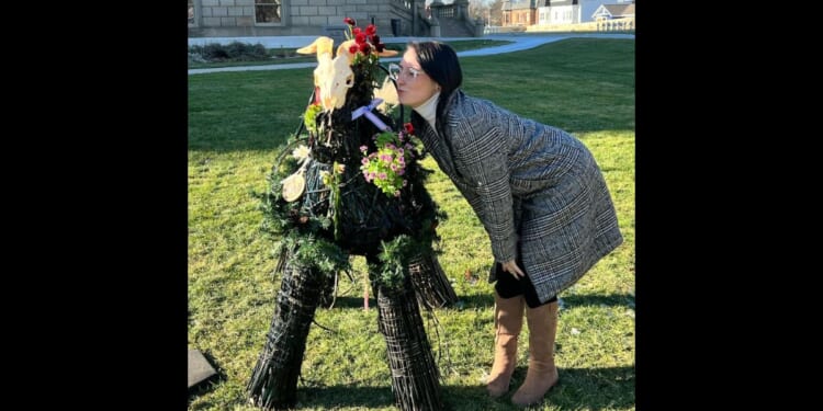 Samantha Skorka kisses a satanic display at the Michigan state Capitol in Lansing.