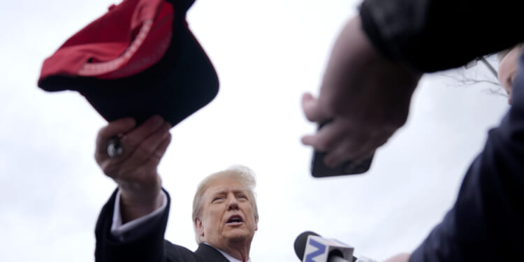 Republican presidential candidate former President Donald Trump hands off a signed hat during a campaign stop in Londonderry, New Hampshire, on Tuesday.