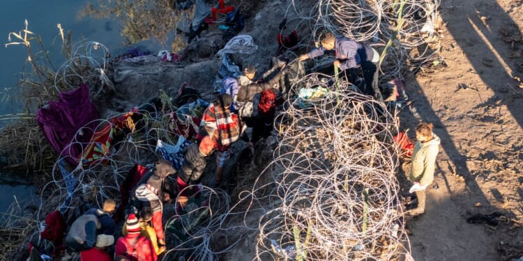 mmigrants climb through razor wire after crossing the Rio Grande from Mexico on Dec. 18 in Eagle Pass, Texas. A surge as many as 12,000 immigrants per day crossing the U.S. southern border has overwhelmed U.S. immigration authorities in recent weeks.