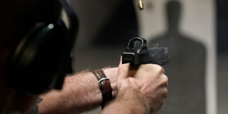 A man fires his pistol at an indoor shooting range in Roseville, California.