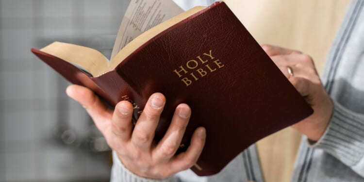 A stock photo shows a man holding and reading the Bible.