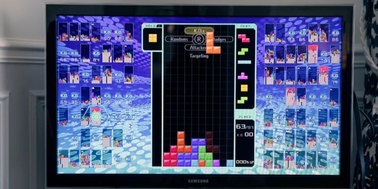 A photo illustration depicts a gamer playing the game Tetris 99.