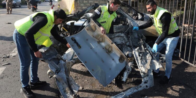 Civil defense workers remove parts of a destroyed car in the southern town of Bazouriyeh, Lebanon, Saturday. An Israeli drone strike on the car near the Lebanese southern port city of Tyre killed two people, the state-run National News Agency reported.