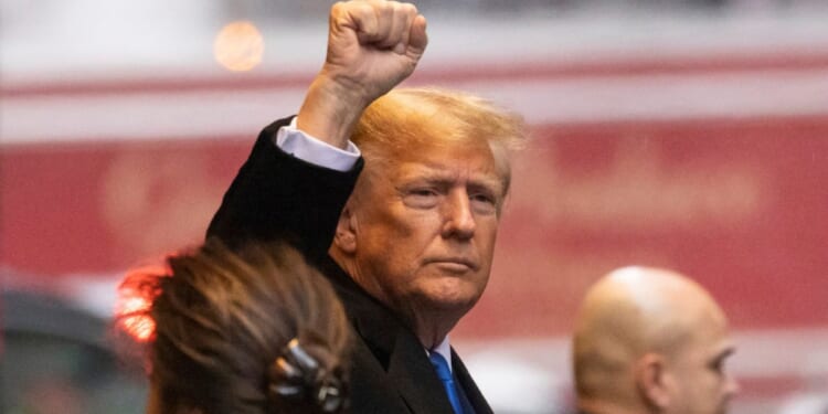 Former President Donald Trump raises his fist as he leaves his apartment building Thursday in New York.