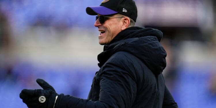 Michigan head coach Jim Harbaugh walks the field before Saturday's NFL football AFC divisional playoff game between the Baltimore Ravens and the Houston Texans in Baltimore.