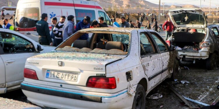 destroyed cars and emergency services near the site where two explosions struck a crowd in Iran