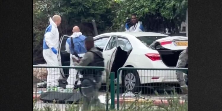 Investigators examine one of the carjacked vehicles used in the attack while armed soldiers stand by.