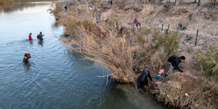 Immigrants climb up the bank of the Rio Grande while crossing from Mexico into the United States near Eagle Pass, Texas, on Jan. 7.