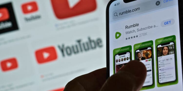 A photo illustration shows the Rumble app download page on a smartphone against a YouTube logo background in Los Angeles on March 29.