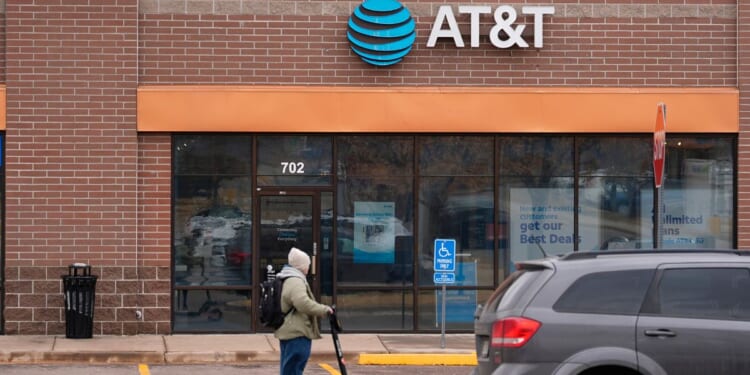 a man riding an electric scooter past an AT&T store