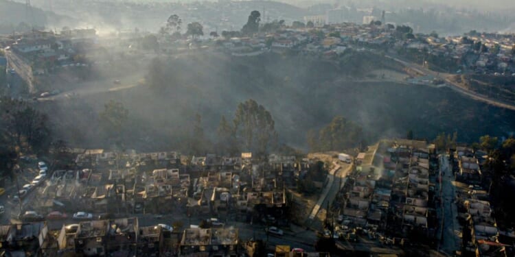 Smoke raises from burned-out houses Saturday after a forest fire reached the Villa Independencia neighborhood in Vina del Mar, Chile.