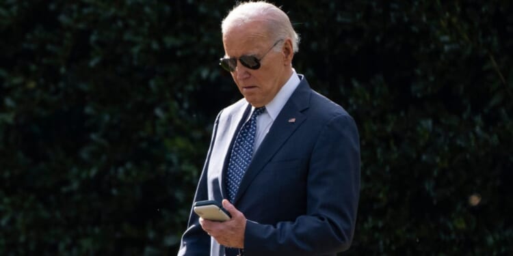 President Joe Biden looks at his phone as he walks to board Marine One on the South Lawn of the White House in Washington on Feb. 8.