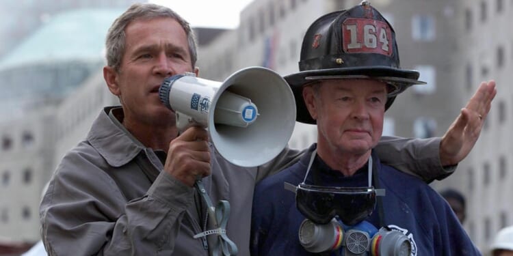 Then-President George W. Bush, left, stands next to retired firefighter Bob Beckwith as he speaks to firefighters and volunteers at the site of the World Trade Center in New York City on Sept. 14, 2001.