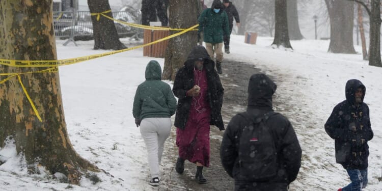 People walk through the snow to and from Manhattan at a temporary shelter for migrants on Randall's Island in New York, on Jan. 19.