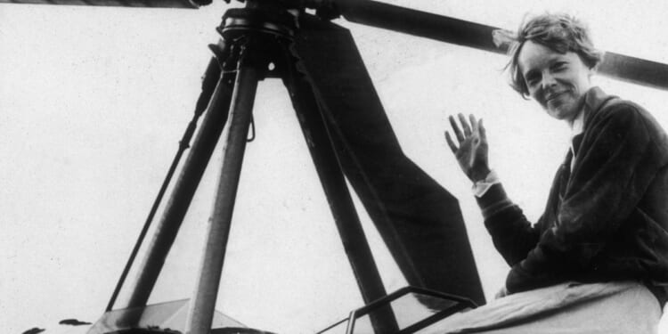 American aviator Amelia Earhart, the first woman to complete a solo transatlantic flight, waves as she emerges from the cockpit of a rotorcraft in Newark, New Jersey, in 1935.