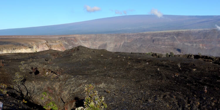 Hawaii's Mauna Loa volcano, background, towers over the summit crater of Kilauea volcano in Hawaii Volcanoes National Park on the Big Island on April 25, 2019.