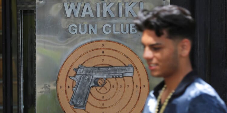 A man is shown walking past a gun club on June 23, 2022, in Honolulu. A ruling by Hawaii's high court saying that a man can be prosecuted for carrying a gun in public without a permit in an apparent rebuke of a U.S. Supreme Court decision that expanded gun rights nationwide.