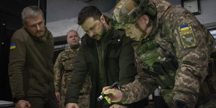 Ukrainian President Volodymyr Zelenskyy (center) and Col.-Gen. Oleksandr Syrskyi (far right) look at a map during a meeting in the front-line city of Kupiansk, Ukraine, on Nov. 30, 2023.