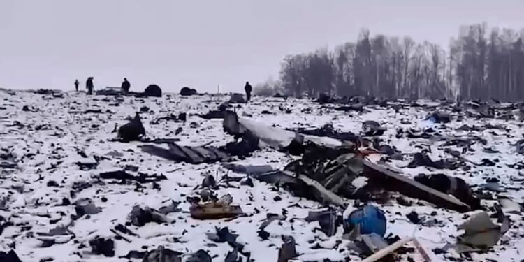 Russian Investigative Committee employees walking near wreckage of a Russian military Il-76 plane