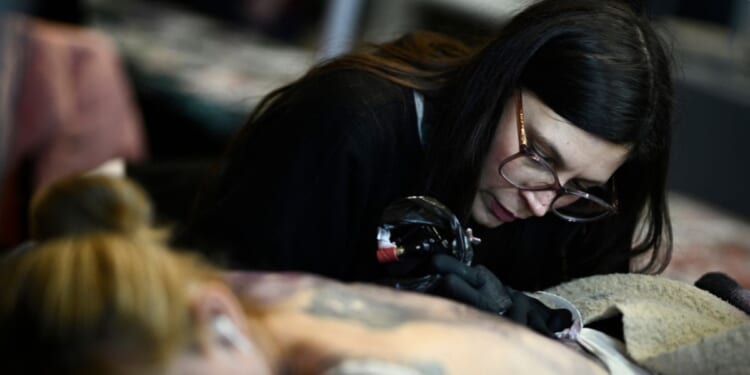 French tattoo artist Norma tattoos a woman's back during the Tattoo Planetarium 2024 edition in Paris, France, on Feb. 2.