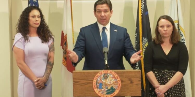 Florida Gov. Ron DeSantis is flanked by two of the late Jeffery Epstein's victims, Haley Robson, left, and Jena-Lisa Jones, after signing a bill Thursday into law that officially authorizes the release of documents from a grand jury investigation in Palm Beach County regarding Epstein's sexual assault of underage girls.