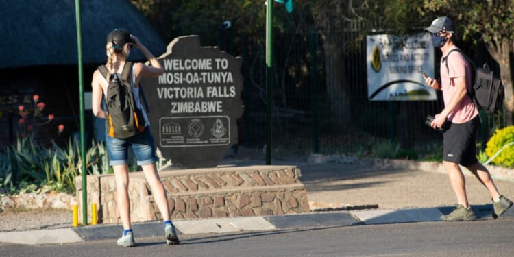 Tourists stand at the entrance to Zimbabwe’s Victoria Falls National Park, in August 2021.