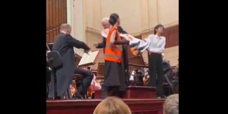 During a live orchestral concert in Warsaw, Poland, the conductor ripped a protest sign away from two climate change activists when they interrupted the perfomance. (@WojPawelczyk / X screen shot)