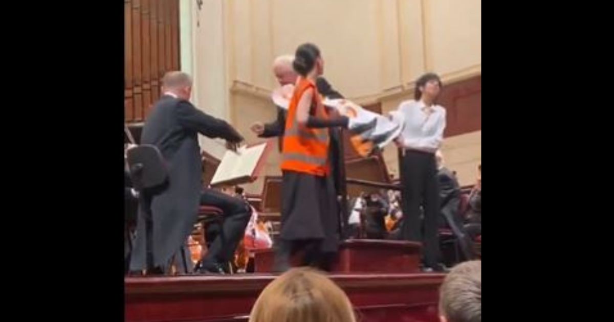 During a live orchestral concert in Warsaw, Poland, the conductor ripped a protest sign away from two climate change activists when they interrupted the perfomance. (@WojPawelczyk / X screen shot)