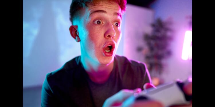 A man with a surprised expression on his face holding a video game controller.