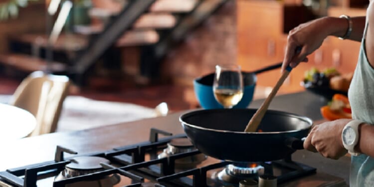 A woman cooking over a gas burner.