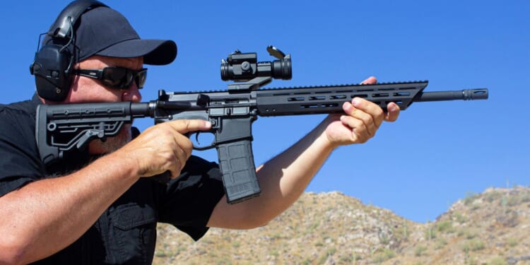 A stock photo shows a man firing an AR-15-style rifle at a range.