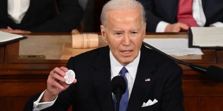 President Joe Biden holds a Laken Riley button while delivering the State of the Union address in the House Chamber of the U.S. Capitol in Washington, D.C. Thursday.