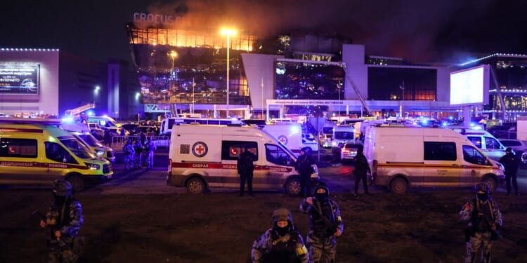 Law enforcement officers are seen deployed outside the burning Crocus City Hall in Krasnogorsk, outside Moscow, on Friday.