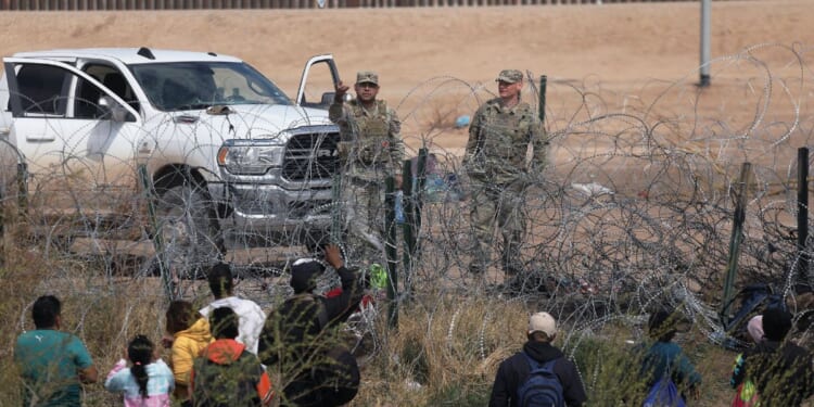 Texas National Guard members prevent illegal immigrants from Venezuela from moving beyond a barbed-wire fence into the United States near El Paso after they crossed the Rio Grande on Feb. 29.