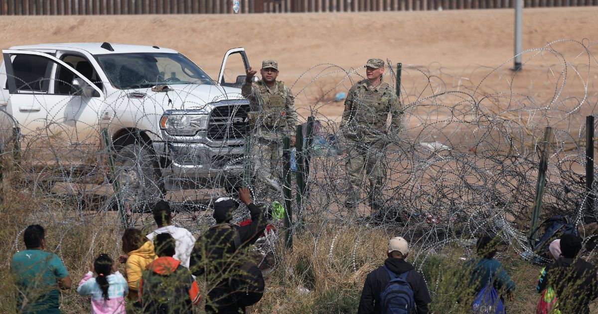 Texas National Guard members prevent illegal immigrants from Venezuela from moving beyond a barbed-wire fence into the United States near El Paso after they crossed the Rio Grande on Feb. 29.