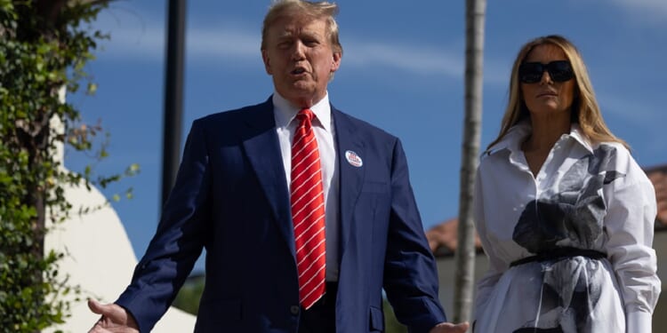 Former U.S. President Donald Trump stands with former first lady Melania Trump as he addresses reporters Tuesday outside a polling station in Palm Beach, Florida.