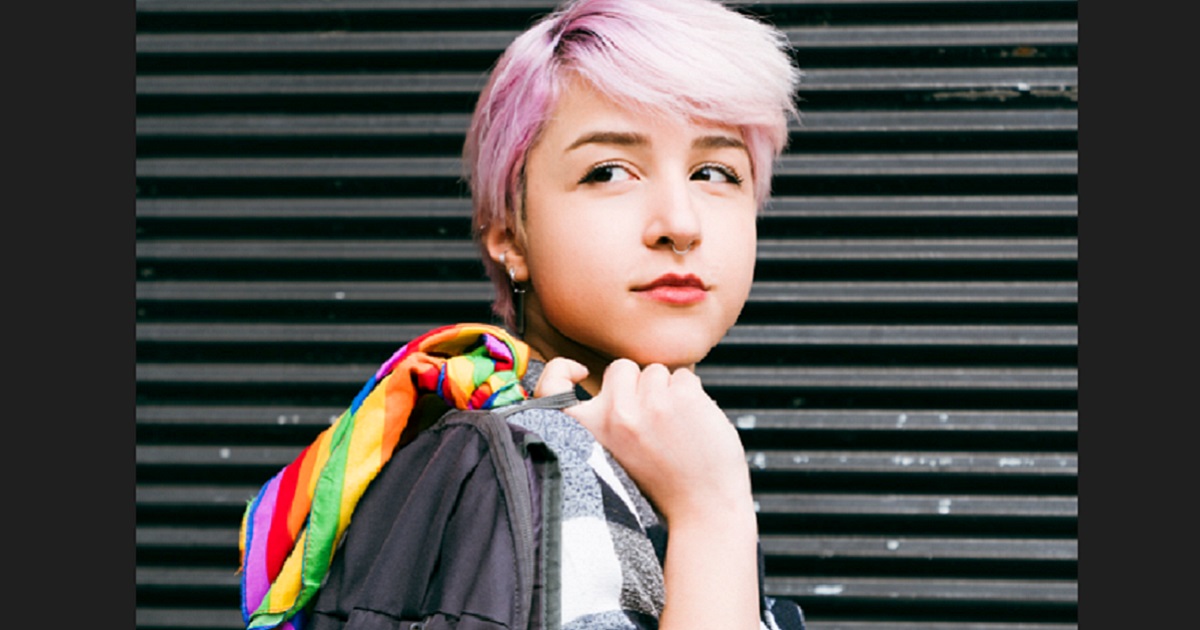 A young person of indeterminate gender with pink hair looking pensive.