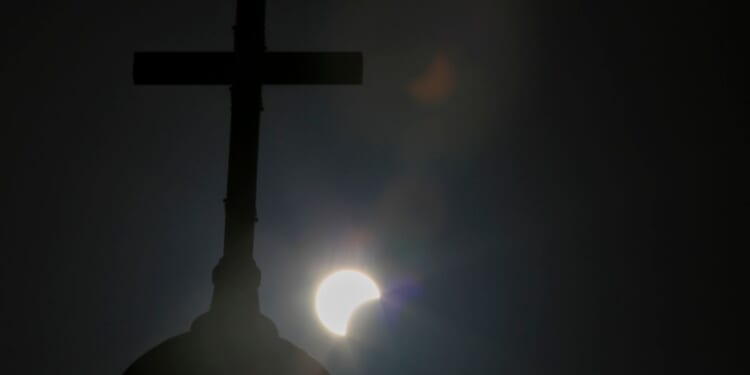 A partial solar eclipse is seen behind a cross on the steeple of the St. George church in downtown Beirut, Lebanon, June 21, 2020.