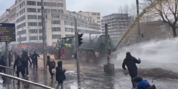 During a protest last week in Brussels, Belgium, farm vehicle sprays liquid manure while a police water cannon tries to disperse the waste.