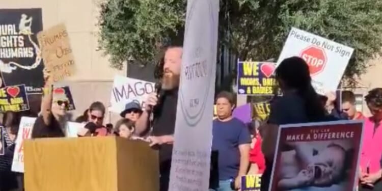 Pastor Jeff Durbin, center, of Apologia Church in Mesa, Arizona, was not deterred by an abortion protester, center, who shouted slogans as he prayed outside the state capitol building.