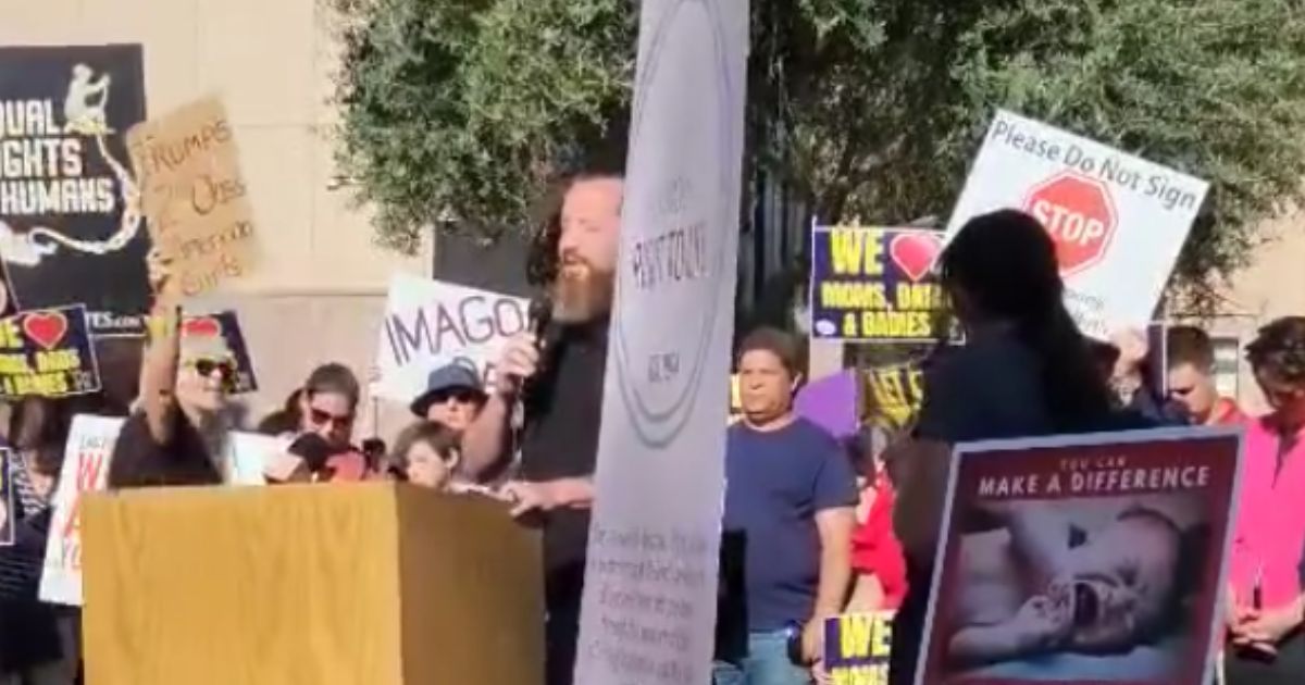 Pastor Jeff Durbin, center, of Apologia Church in Mesa, Arizona, was not deterred by an abortion protester, center, who shouted slogans as he prayed outside the state capitol building.