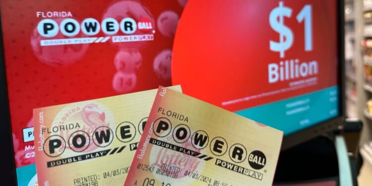 Powerball tickets are shown in front of a screen displaying the estimated Powerball jackpot in Surfside, Florida, on Wednesday.