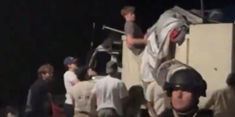 Young men help remove an encampment set up on the campus of Arizona State University.