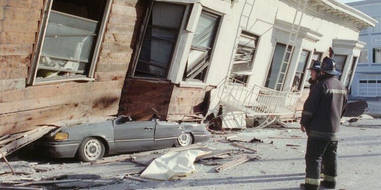 Two firemen survey the damage from a San Francisco house that collapsed, crushing a car, in the city's Marina District after a quake rocked California October 17, 1989.