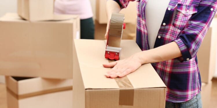 A stock photo shows people packing boxes before a move.