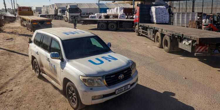 A United Nations vehicle drives past trucks delivering humanitarian aid to Gaza on Feb. 17.