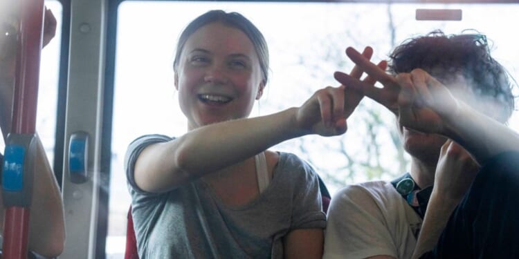 Climate activist Greta Thunberg flashes a V-sign after being detained and driven off in a bus after joining protestors who blocked a road during a climate protest by Extinction Rebellion and other activists in The Hague, Netherlands, Saturday.