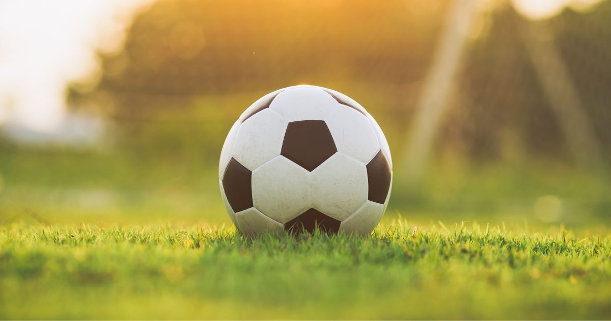 A stock photo shows a soccer ball sitting in the grass.