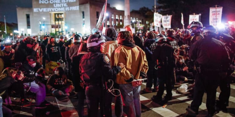 Police officers detain pro-Palestinian protesters who are blocking the street near the home of Senate Majority Leader Chuck Schumer in New York City on Tuesday.